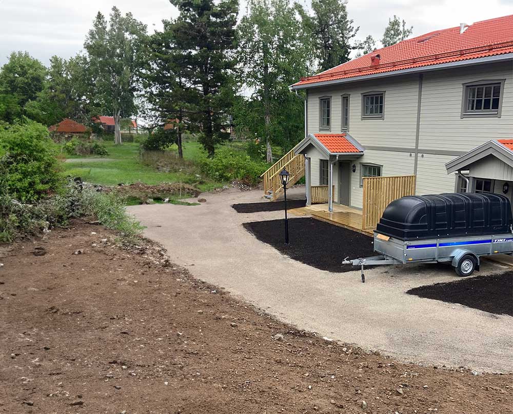 Nylagd jord och grusväg utanför hus